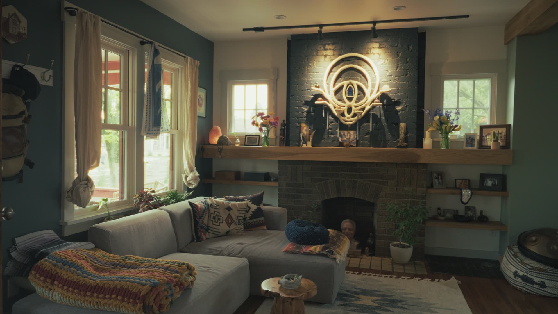 Living room with a grey sectional sofa facing the brick fireplace and custom white oak mantel