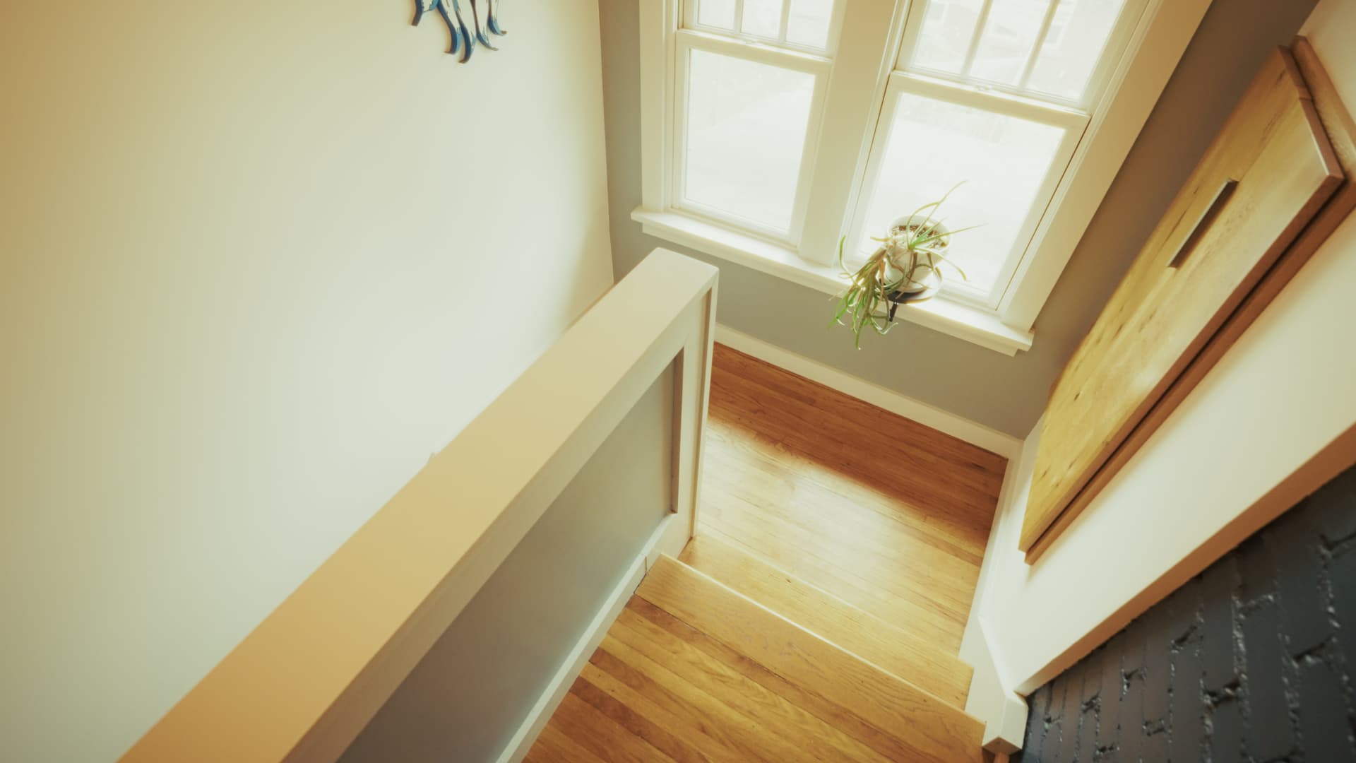 Looking down a light-wood staircase from the upper floor of the main house