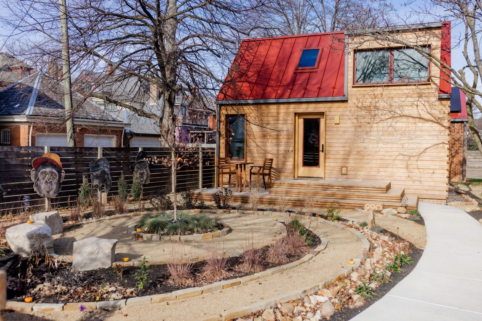 990 Oak Street under soft light: thermally modified wood siding, red metal roof, and high-performance windows