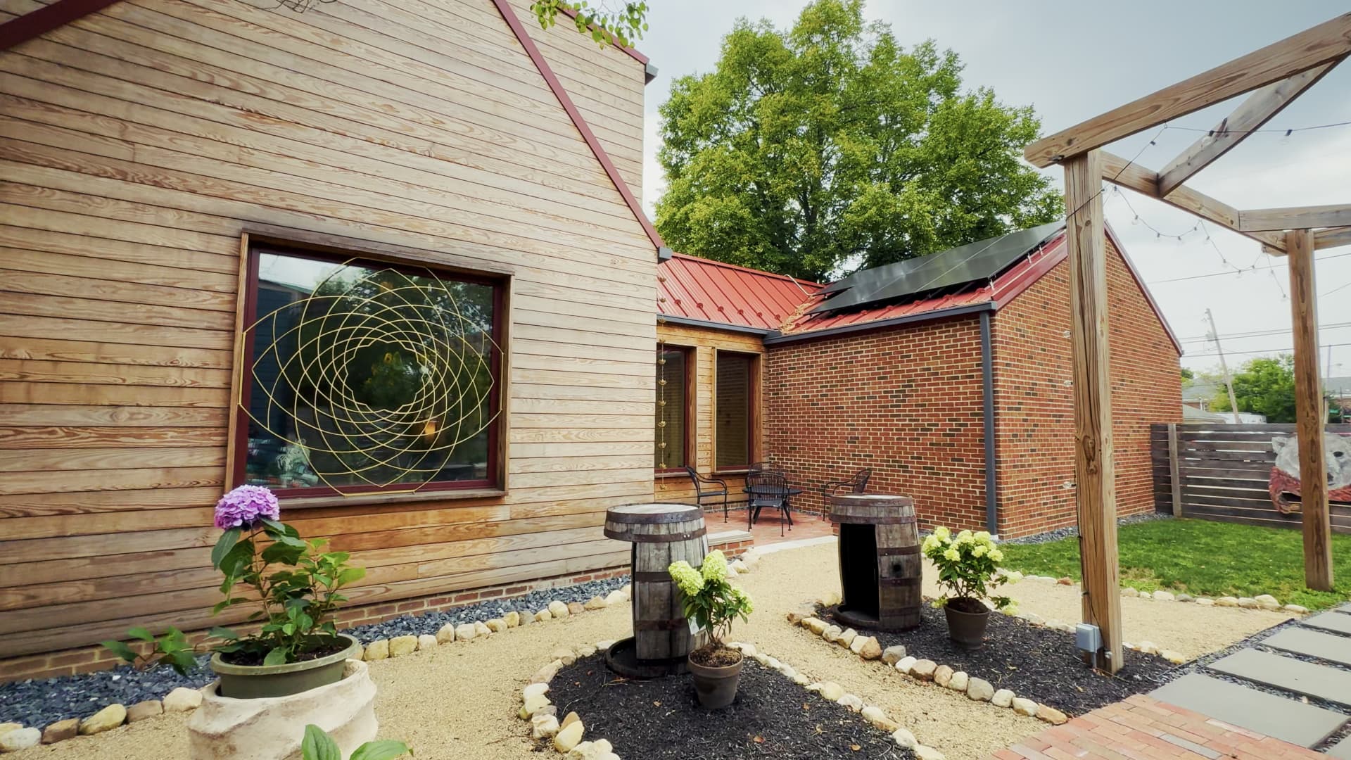 Exterior of 990 Oak with Arbor Wood thermally modified wood siding in natural pine, a sacred geometry motif in the window glazing, and rooftop solar panels