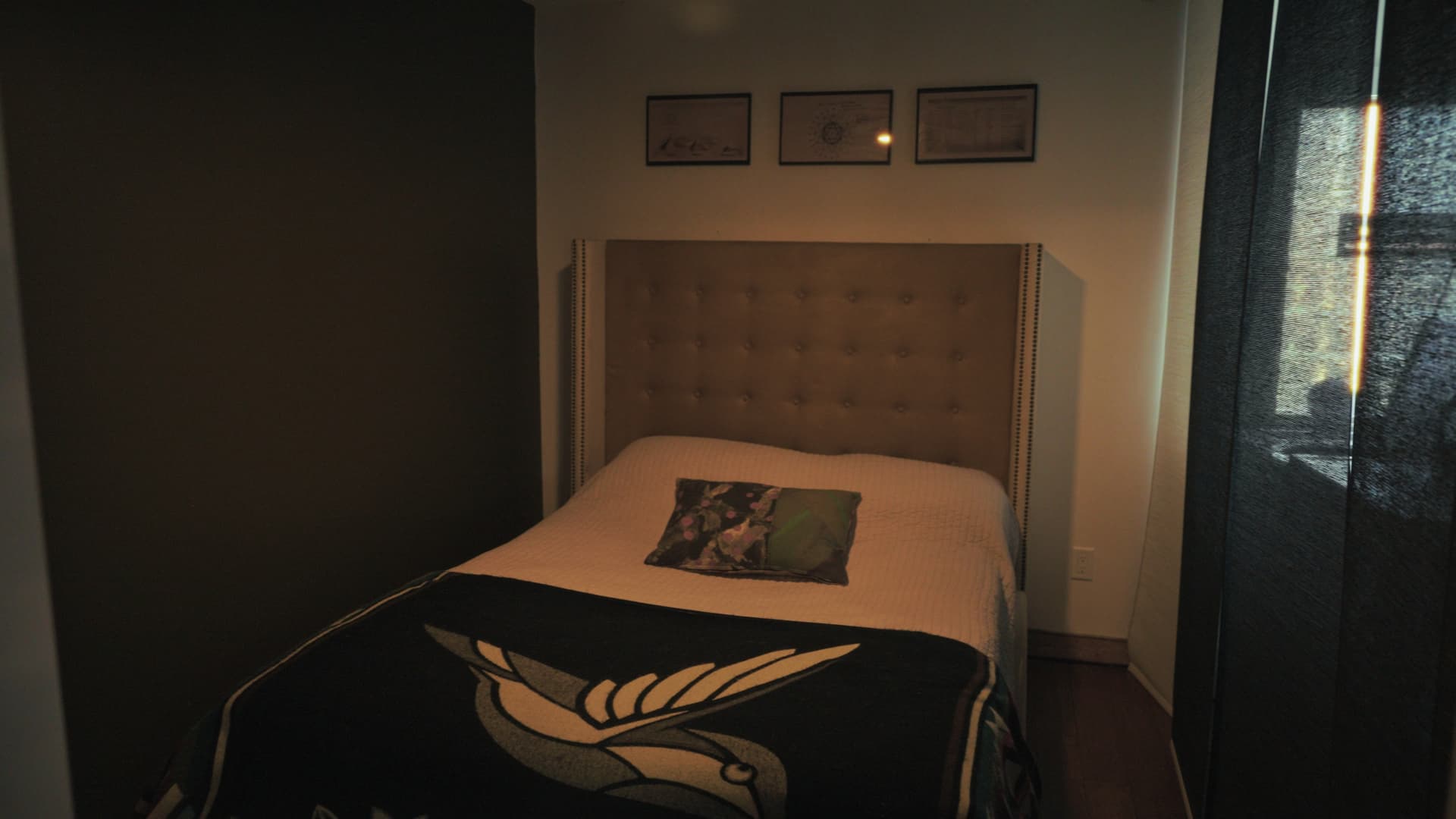 Carriage house bedroom with a tufted headboard against dark painted walls