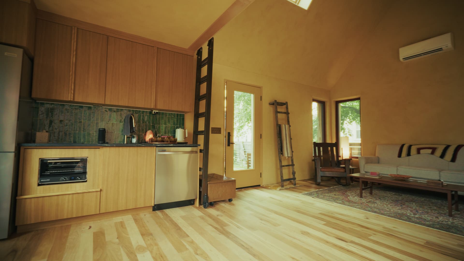 Wide view of the passive house studio kitchen and living area with soapstone counters and handmade teal tile