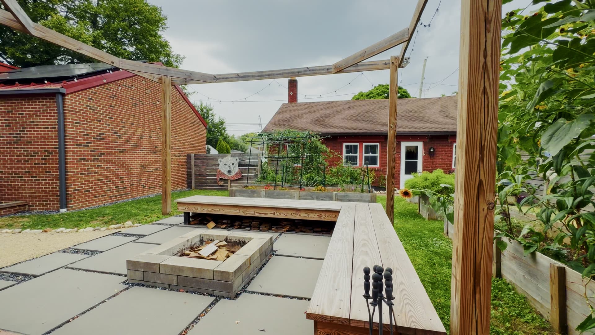 Paver patio with a modern square fire pit ringed by built-in wood bench seating and brick accent banding